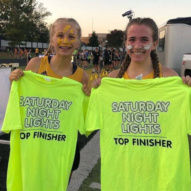 130045246_web1_IMG-1858
Georgetowns Lydia Klump, left, and Lizzy Cahall received top finisher T-shirts for their 3rd and 5th place finishes at this years Saturday Night Lights Cross Country Invite held Sept. 30.